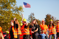 Group of people in orange vests celebrating at a parade.