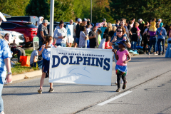 A group of people marching in a parade carrying signs that say 'Dolphins' and 'Marysville Elementary School'.
