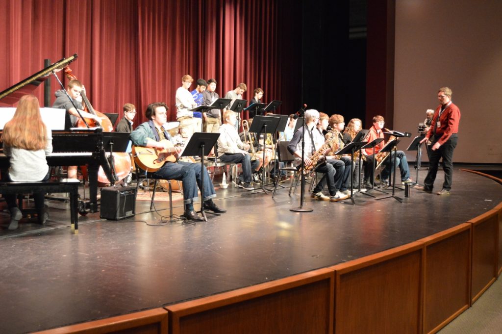 Large group of musicians performing on stage in front of an audience.
