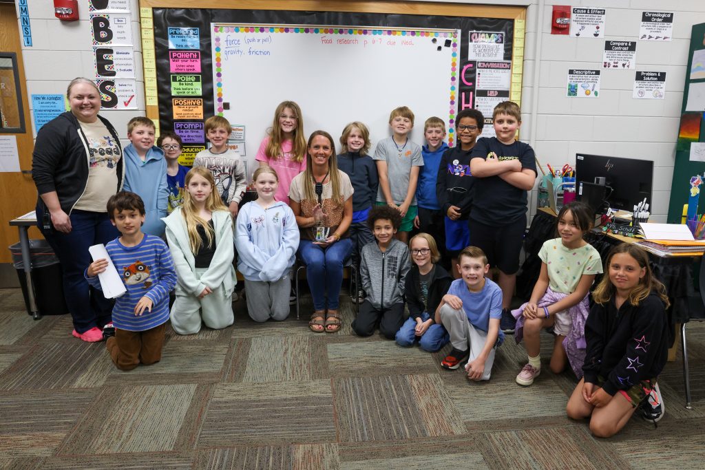 Teachers and students posing in front of a whiteboard for a group picture.
