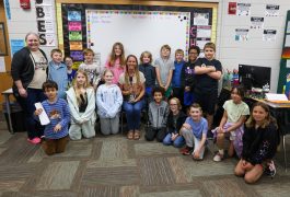 Teachers and students posing in front of a whiteboard for a group picture.