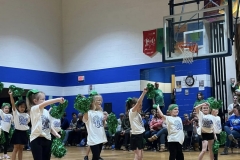 Young cheerleaders performing in gymnasium during basketball game.
