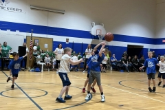 Children playing basketball on a gym court during a game.