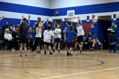 People playing basketball in gymnasium.