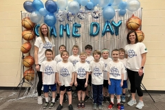 Group of children in front of a sports ball backdrop at a basketball game, posing for a picture.