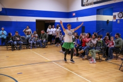 Person in a hula skirt dancing on basketball court.
