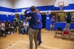 Two men hugging in a gymnasium during a basketball game.