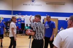 Basketball game in progress, referee and players on court.