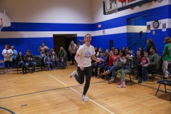 Woman in white shirt running on basketball court.