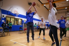 People playing basketball in gymnasium.