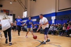 Group of people playing basketball in gymnasium during March Madness event.