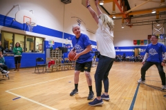 An elderly man is playing basketball in a gymnasium.