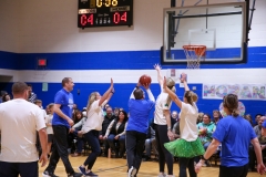 People playing basketball in a gymnasium during a game.