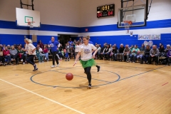 People playing basketball in gymnasium during game.