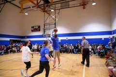 People playing basketball in a gymnasium during a game.