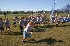 Children running in a field during a fun run event.