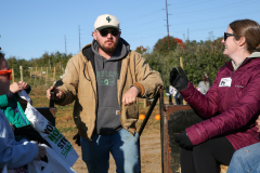 Two people standing in front of a truck at an apple orchard.