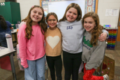 Four girls posing in a classroom for a picture on Valentine's Day.