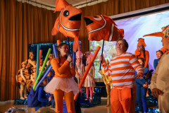 Children in costumes, possibly at a themed event or party, with a large fish balloon and a smaller fish balloon.