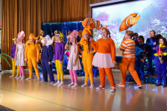 A group of people dressed in costumes, including a clownfish and Nemo, standing on a stage.