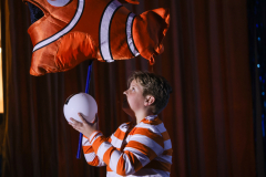 A person in a clownfish costume holding a balloon.