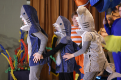 Three people in shark costumes standing together.