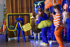 A group of children dressed in costumes, performing on stage.