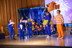 A group of children in costumes on stage, posing for a photo.