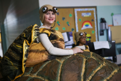 Boy in turtle costume sitting on a chair.