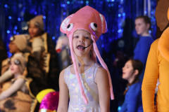A young girl dressed in a pink octopus costume, performing on stage.