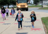 Children walking down a sidewalk on their first day of school.