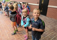 Children in school uniforms posing for a picture on the first day of kindergarten.