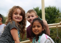 Children posing at a playground on their first day of kindergarten.