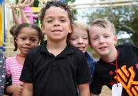 Children posing together on playground equipment, smiling for a group photo.