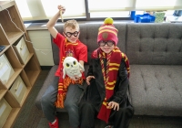 Two children dressed as wizards sitting on a couch.