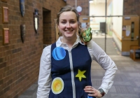 Woman in vest standing in hallway.