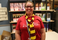 Woman wearing a red shirt and glasses standing in front of a bookshelf filled with books.