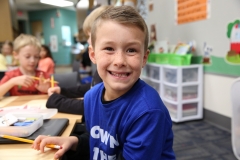 Boy in blue shirt smiling at camera.