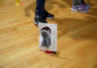 Two people standing on a wooden floor holding a cardboard cutout of a cat.