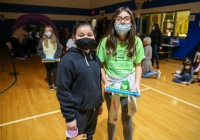 Two people in masks standing in front of a gymnasium.