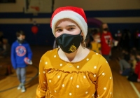 Woman wearing a face mask smiles at camera in gymnasium.