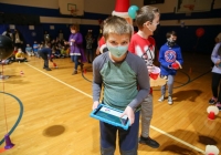 Children in school gymnasium wearing masks, playing with sphero robots.