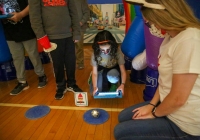 Woman crouching down to interact with a small robot ball.