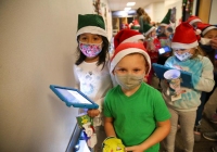 Children in Santa hats holding tablets, one child wearing a mask.