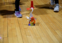 People playing with a toy robot on a wooden floor.