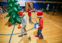 Children in santa hats playing with a sphero robot on a basketball court.