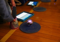 Person holding a Sphero robot in front of a blue mat on the floor.